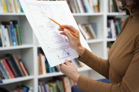 Woman architect working with blueprints in a well-stocked libraryの写真素材
