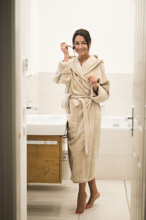 Slim cute young woman in a home robe doing make upの写真素材