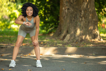 Woman exercising in a park and having a short pauseの写真素材
