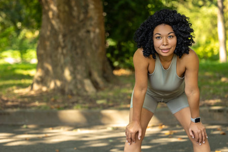 Woman exercising in a park and having a short pauseの写真素材