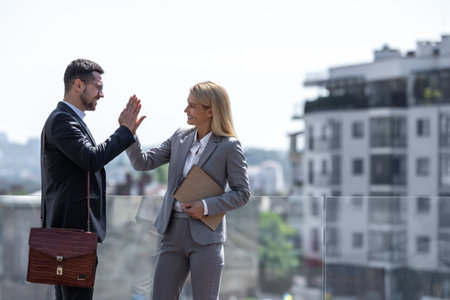 Business partners standing against city buildings and high fiving