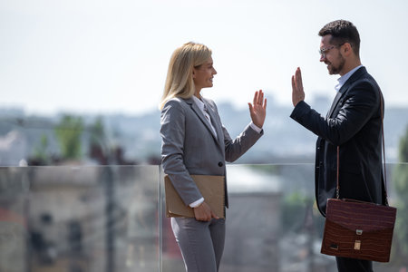 Business partners standing against city buildings and high fivingの写真素材