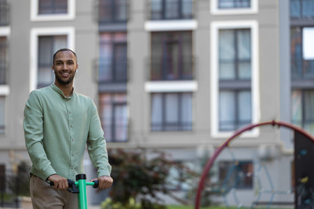 Black man using ecological mean of transportation while resting on city street