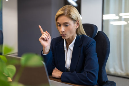 Confident female company executive wearing suit working on computer at workplaceの写真素材