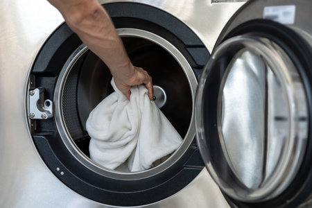 Unrecognizable man washing clothing at industrial laundromat