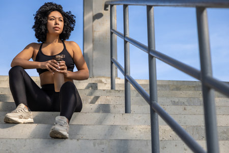 Smiling woman in sportswear resting on the stairs after workout