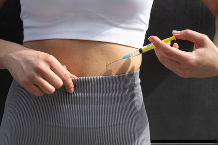 Close up of a woman doing lipolytic injection to her abs