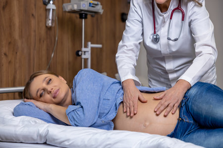 Doctor examining pregnant womans belly and palping it