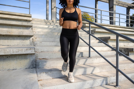 Woman in black sportswear going downwards on the steps