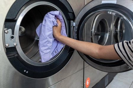 Unrecognizable woman housewife washing clothing at industrial laundromatの写真素材