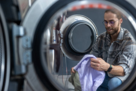 Caucasian man operating washing machine at commercial laundry