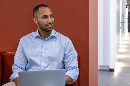 Confident businessman in office hall with laptop