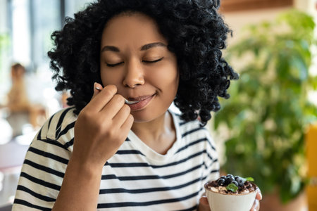 Woman in striped blouse enjoying delicious tiramisuの写真素材
