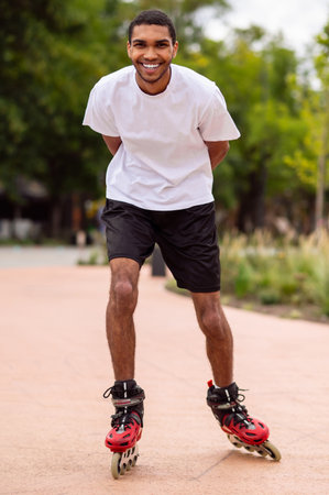 Tall dark-haired young man on rollers in the park having a ride