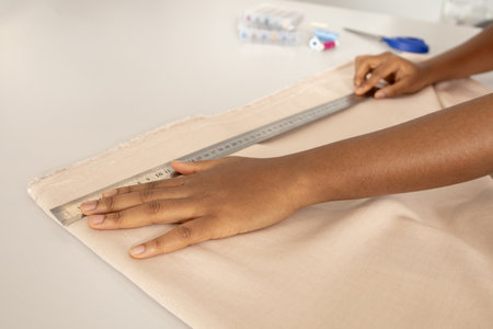 Unrecognizable seamstress woman using measuring tape on the fabric
