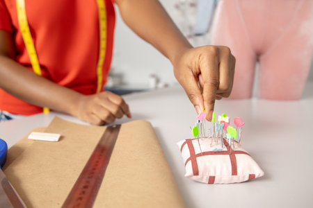 Unrecognizable woman hands sewing fabric with needle at her workshopの写真素材