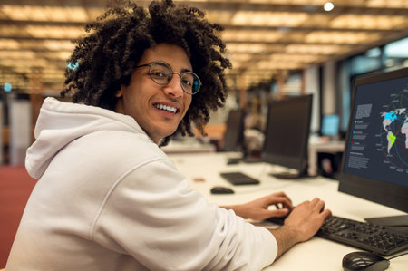 Man student browsing educational software on his computer in university library