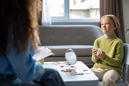 Cute blonde boy having a session of speech exercises with speech therapistの写真素材