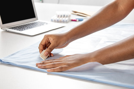 Dressmaker and stylist sewing stylish blue dress or shirt in a professional studioの写真素材