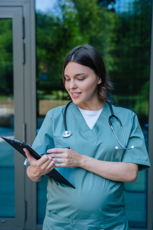 Pregnant young doctor on the clinic building backgroundの写真素材
