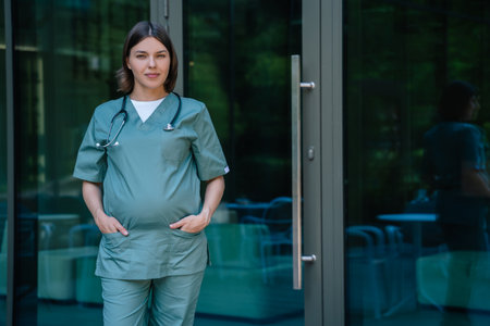 Pregnant woman in scrubs standing in front of the clinicの写真素材