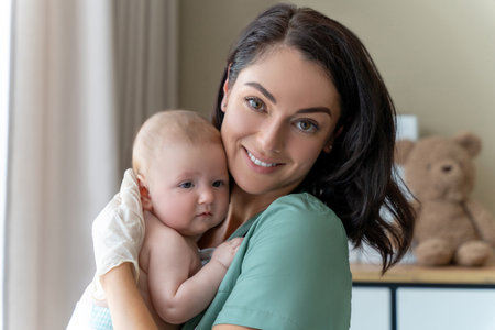 Beautiful nurse medical worker in gloves holding newborn baby in handsの写真素材