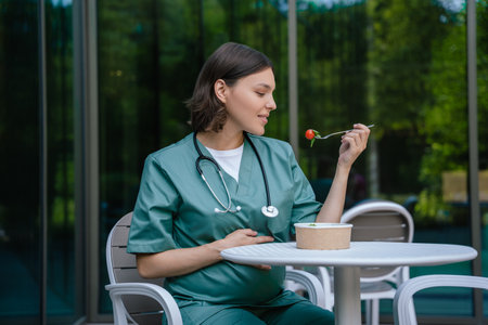 Pretty young female doctor having lunch and looking enjoyedの写真素材
