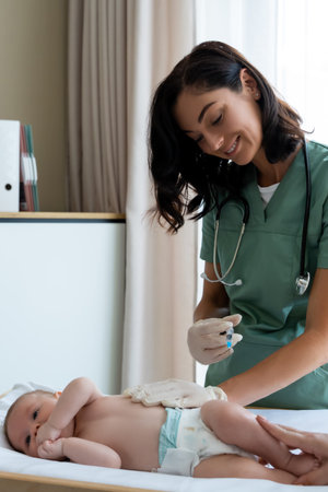 Pediatrician administers an injection to baby during routine checkup at hospitalの写真素材