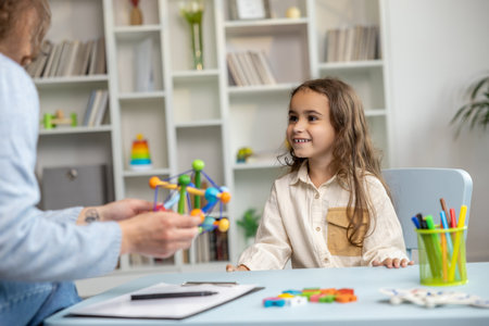 Cute long-haired girl looking busy while having a tutorial with a speech therapistの写真素材