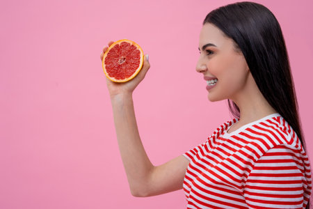Waist up of a young woman with grapefruit in handの写真素材