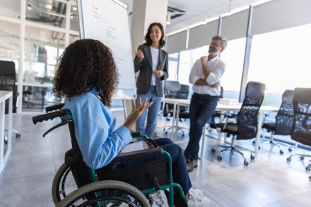Executive woman with disability in wheelchair in office giving presentation on strategyの写真素材