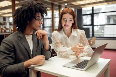 Students working together on the project in the library and looking involvedの写真素材