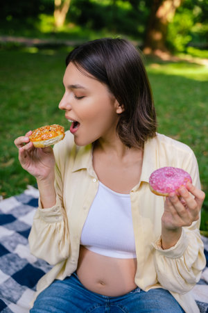 Young pregnant woman eating donuts and feeling happy