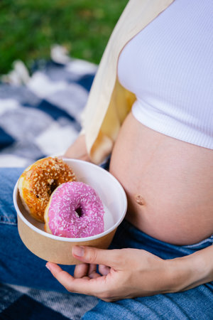 Close up of a pregnant woman holding a bowl with donutsの写真素材