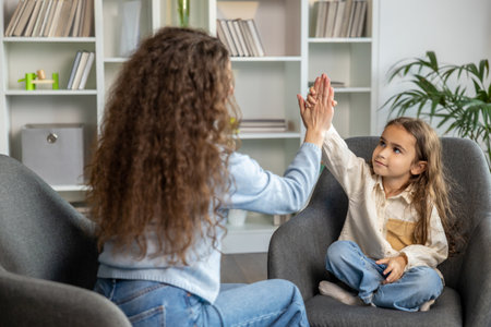 Long-haired woman and a cute little girl doing high five and looking positive