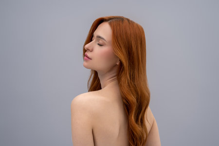 Young woman with long ginger hair on a grey backgroundの写真素材