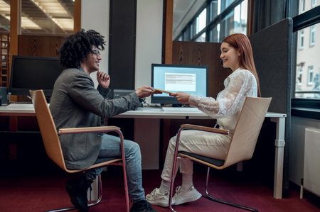 Young man and young woman working together on the project in the officeの写真素材