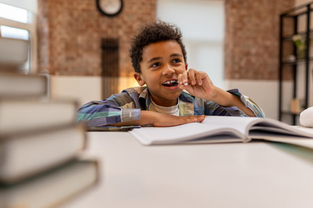 Dark-skinned cute boy doing lessons and looking involvedの写真素材
