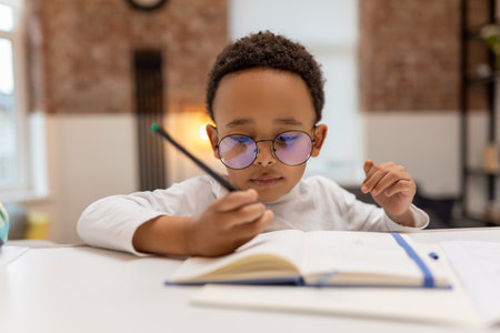 African american boy doing lessons and writing something in a notebook