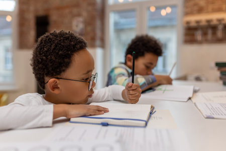 African american boy doing lessons and writing something in a notebookの写真素材