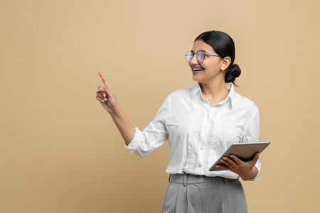 Satisfied woman holding digital tablet pointing at advertisement areaの写真素材