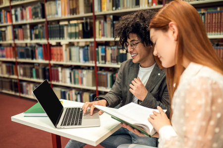 Ginger cute girl working in the library with her friendの写真素材