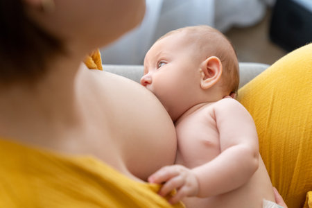 Unrecognizable mother carefully breastfeeding her baby while sittingの写真素材