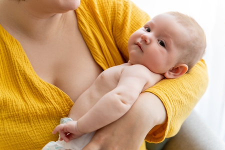 Unrecognizable mother carefully breastfeeding her baby while sitting