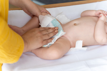 Mother changing her babys diaper taking care of her newborn childの写真素材