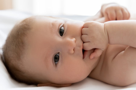 Cute infant baby girl or boy looking at camera with curious eyesの写真素材