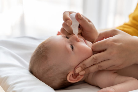 Woman using nasal spray for infant baby loving mother taking care of her newborn childの写真素材