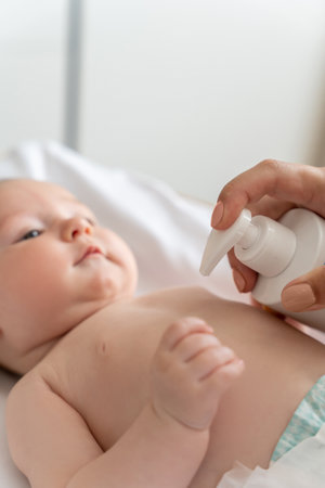 Mother using cream for taking care of newborn baby bodyの写真素材