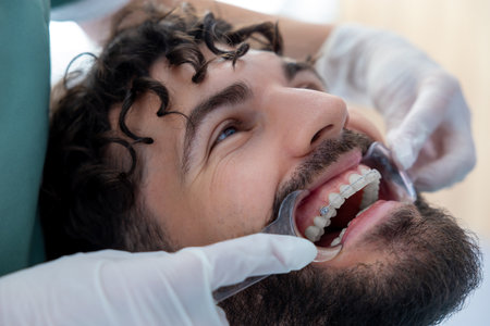 Stomatologist doing check of patientâs teeth with professional expertise while managing dental toolsの写真素材