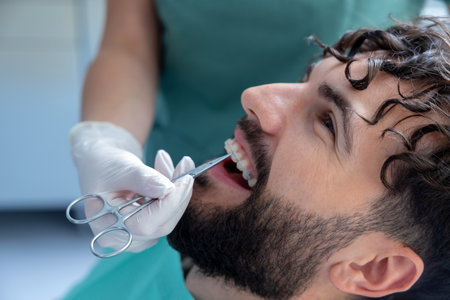 Stomatologist doing check of patientâs teeth with professional expertise while managing dental toolsの写真素材